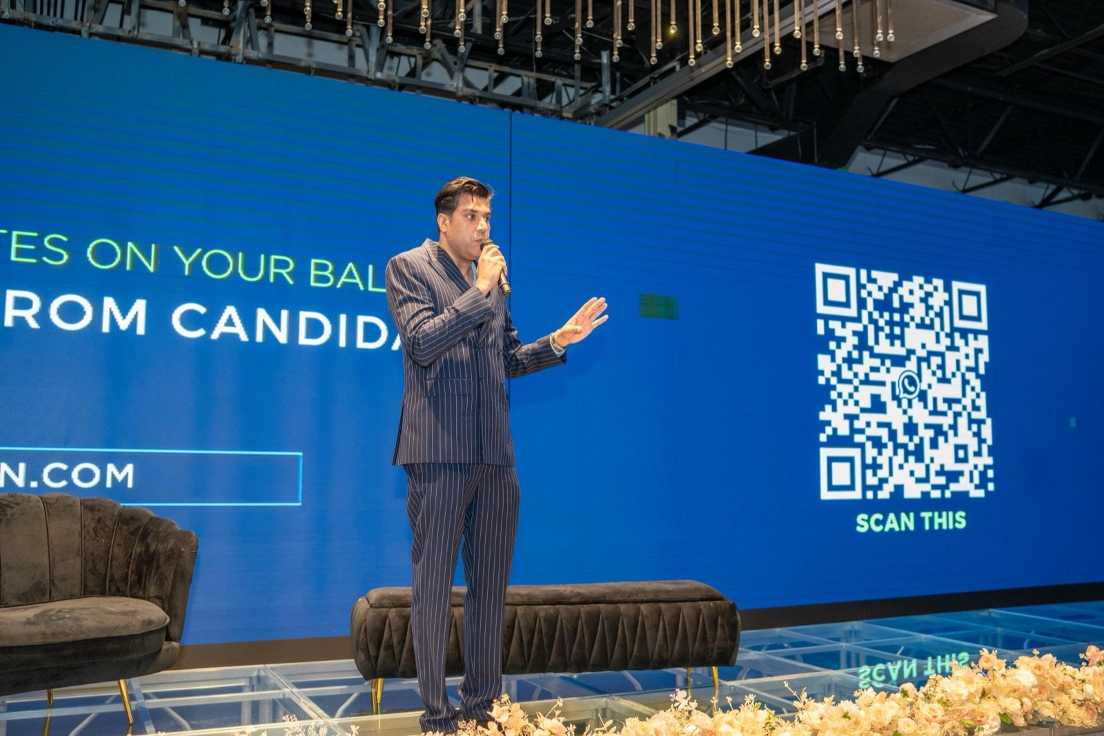Votcen founder on stage at the Candidate Forum, with the ballot and a scan-this QR code on the screen behind